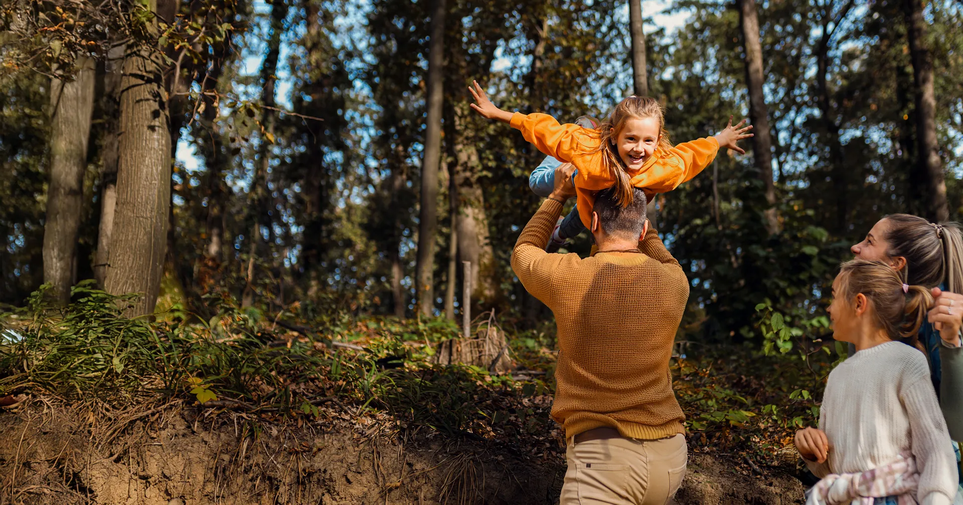Een lachend gezin van vier geniet van de natuur tijdens een wandeling in het bos.